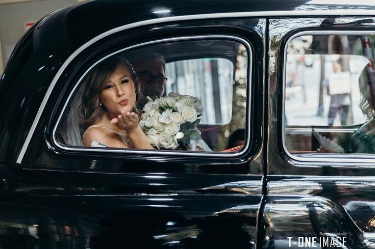 a bride and groom are in an old black car