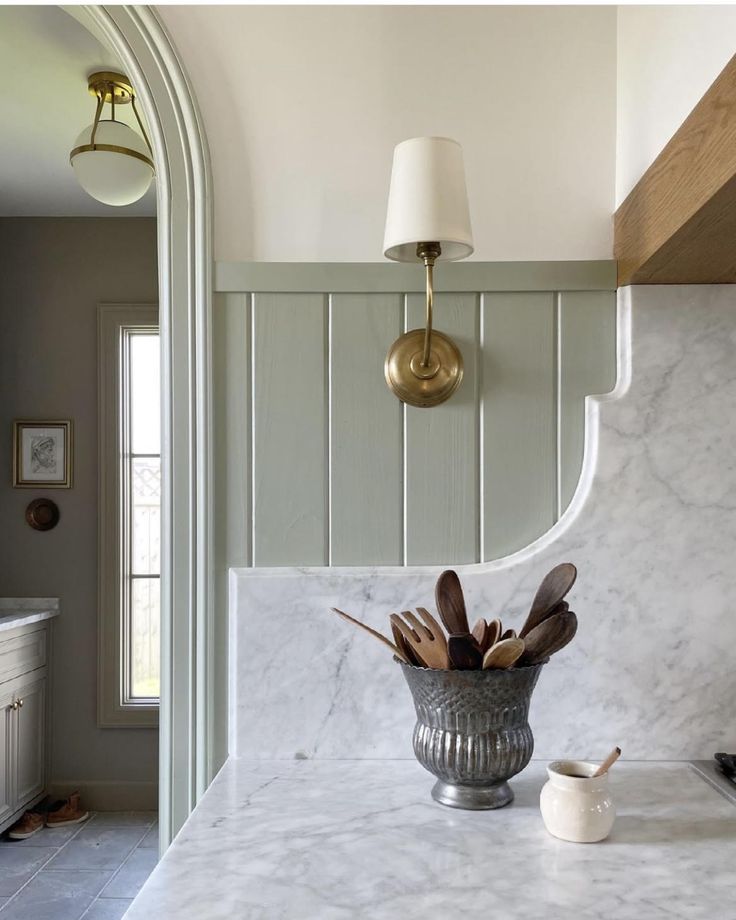 a kitchen with marble counter tops and gold fixtures on the wall, along with a vase filled with utensils