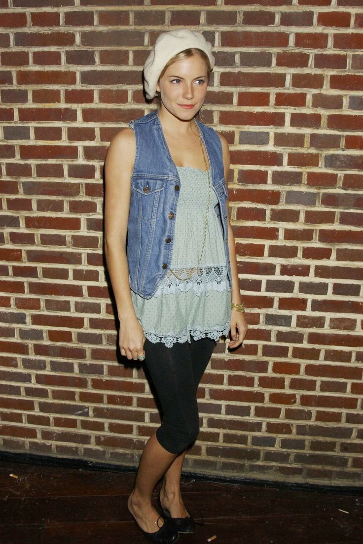 a woman standing in front of a brick wall