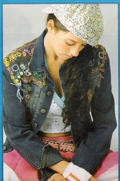 a woman wearing a jean jacket and white hat sitting on top of a pink blanket