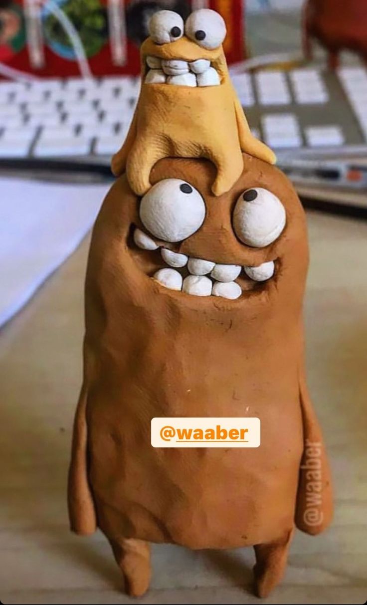 a clay sculpture of an orange and yellow monster with two eyes on it's head