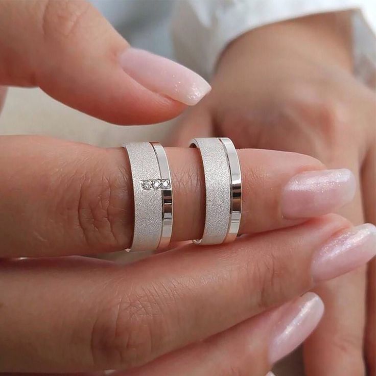 two people holding hands with wedding rings on their fingers and one is wearing a diamond ring