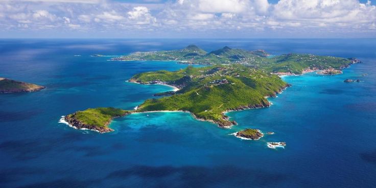 an aerial view of several small islands in the middle of the ocean with blue water