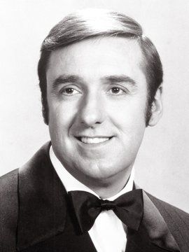 a man in a tuxedo and bow tie smiling at the camera with his eyes wide open