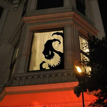 a building with a clock tower at night and a silhouette of a demon on the window