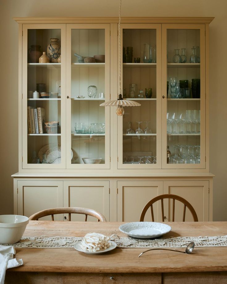 a dining room table with plates and bowls on it, next to a china cabinet