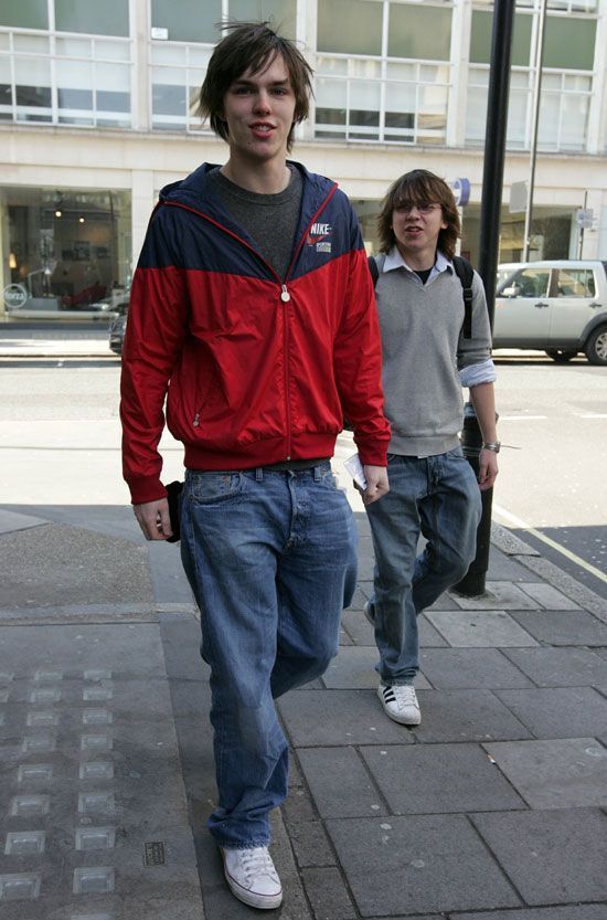 two young men walking down a sidewalk next to each other