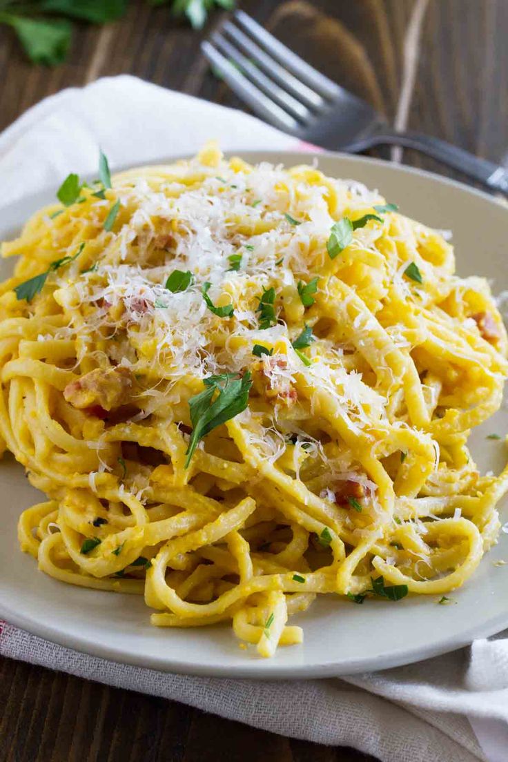 a plate of pasta with parmesan cheese and herbs on the side next to a fork