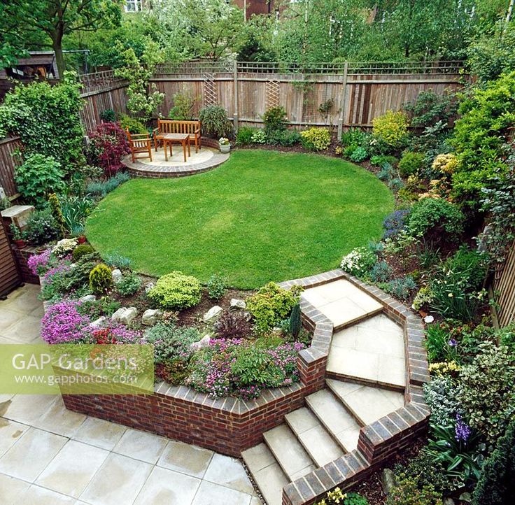 a small garden with steps leading up to the lawn and seating area on either side