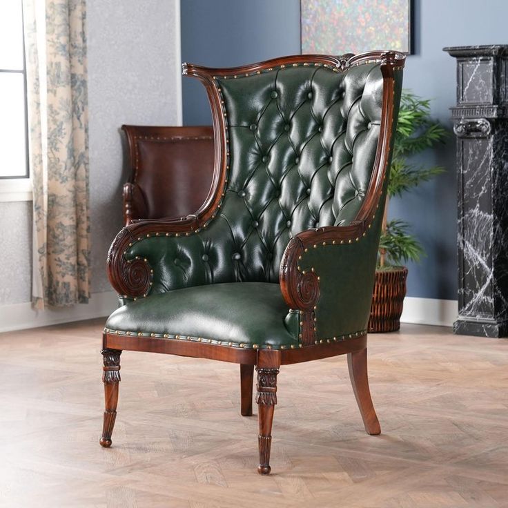 a green leather chair sitting on top of a hard wood floor next to a fireplace