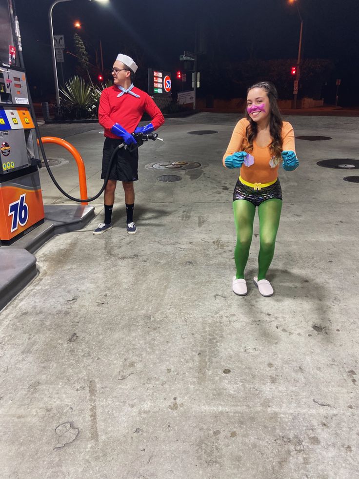 a man and woman are standing in front of a gas pump