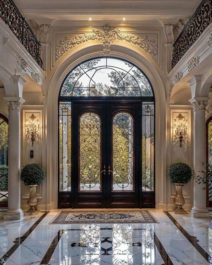 an ornate entry way with two double doors and marble flooring, surrounded by glass windows