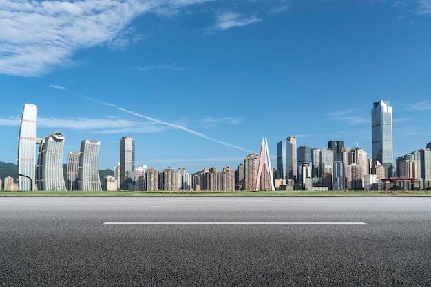 an empty highway with the city skyline in the backgroung and blue sky