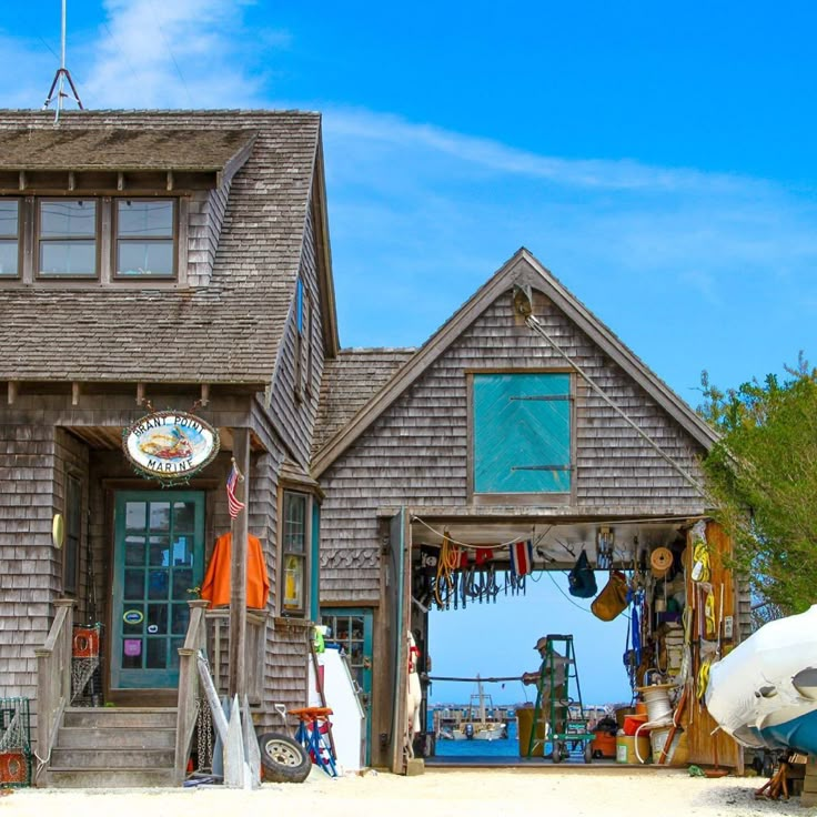 a boat is parked in front of a house on the beach with an umbrella and kayak