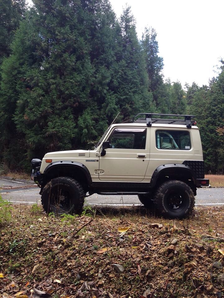 an off - road vehicle is parked on the side of the road in front of some trees