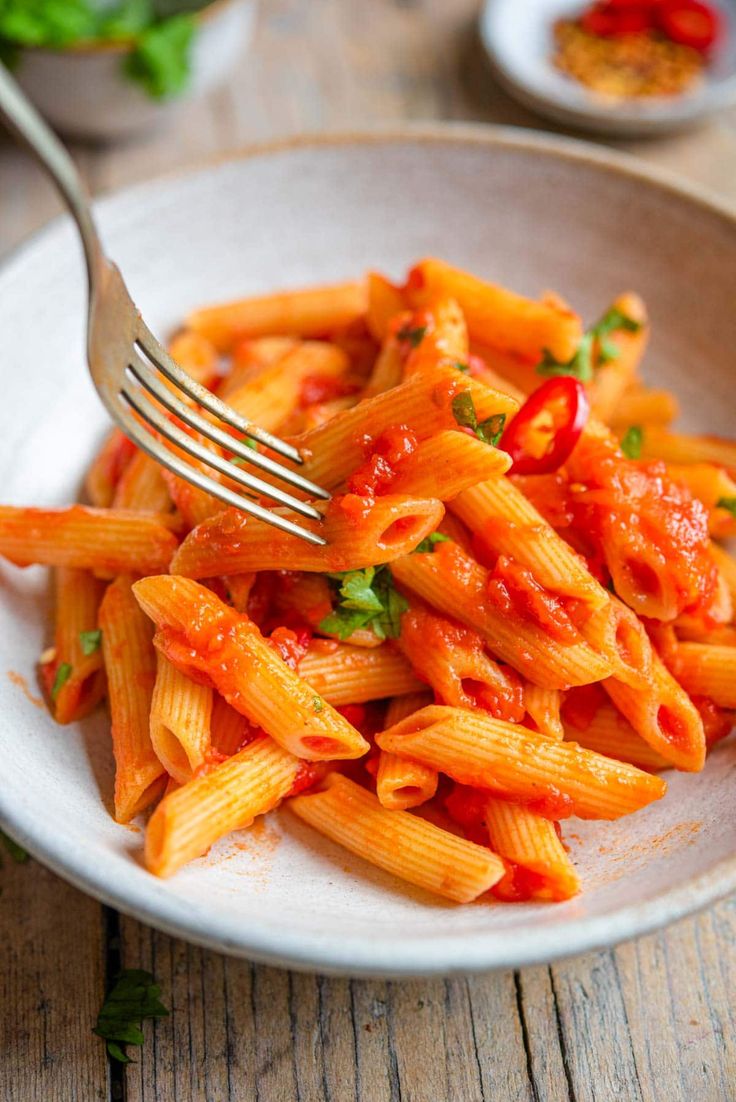 a white plate topped with pasta covered in sauce and garnished with parsley