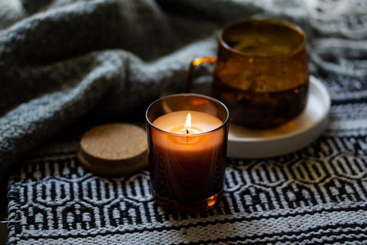 a lit candle sitting on top of a table next to a cup and saucer