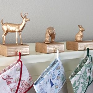 three christmas stockings hanging on a shelf with gold deer figurines in the background