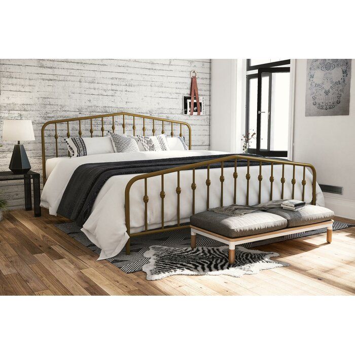 a bedroom with white brick walls and hardwood floors, including a bed frame that has black iron designs on it