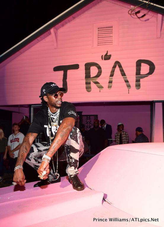 a man sitting on top of a pink car in front of a sign that says trap