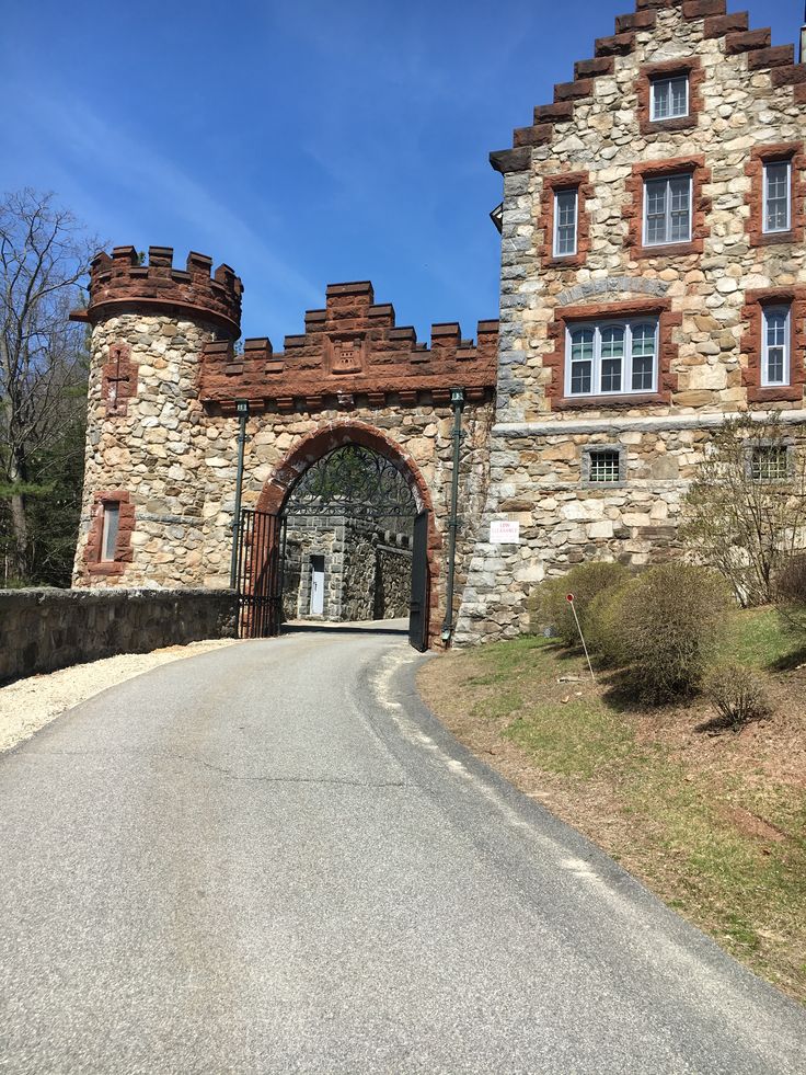 an old stone building with a gate in front of it on a road that leads to the entrance