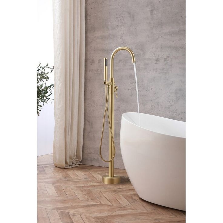 a bathtub with a gold faucet next to a window