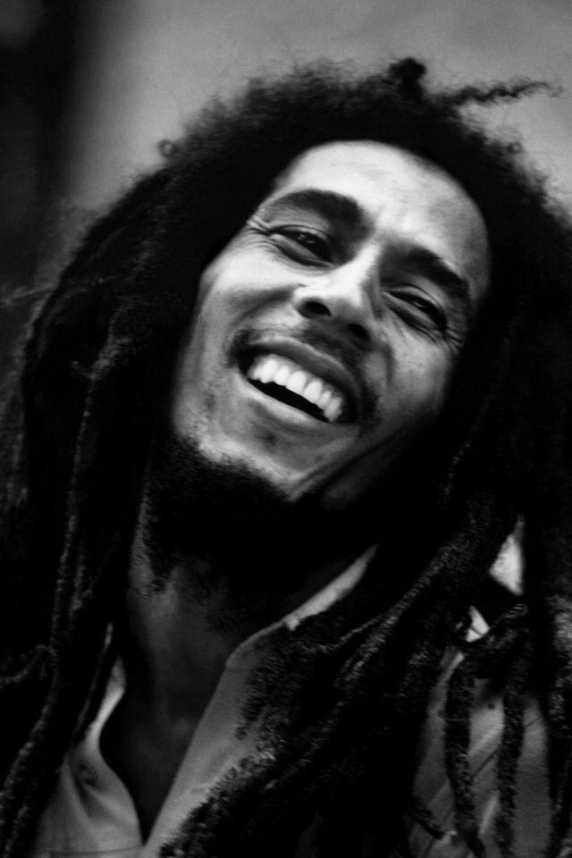 a black and white photo of a man with dreadlocks smiling at the camera