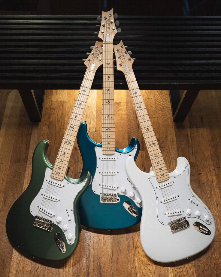 two electric guitars sitting on top of a wooden floor