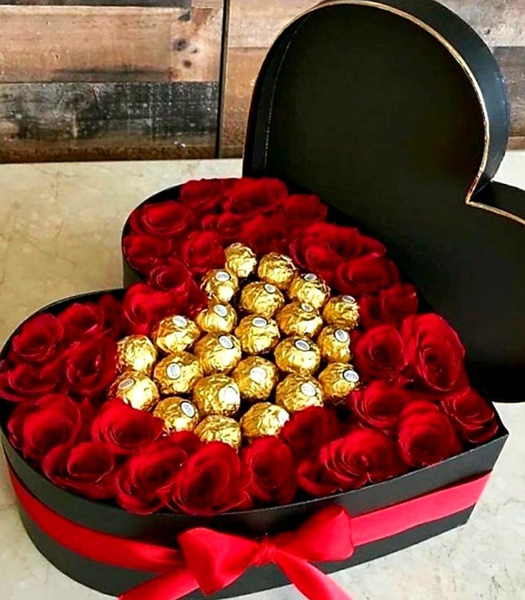 a heart shaped box filled with chocolates and roses