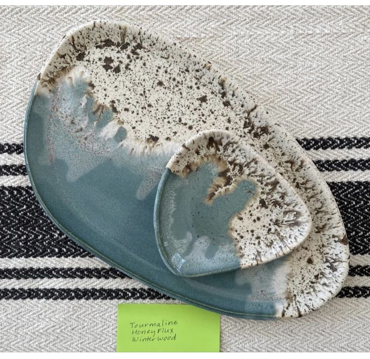 two blue dishes sitting on top of a white and black striped table cloth next to each other