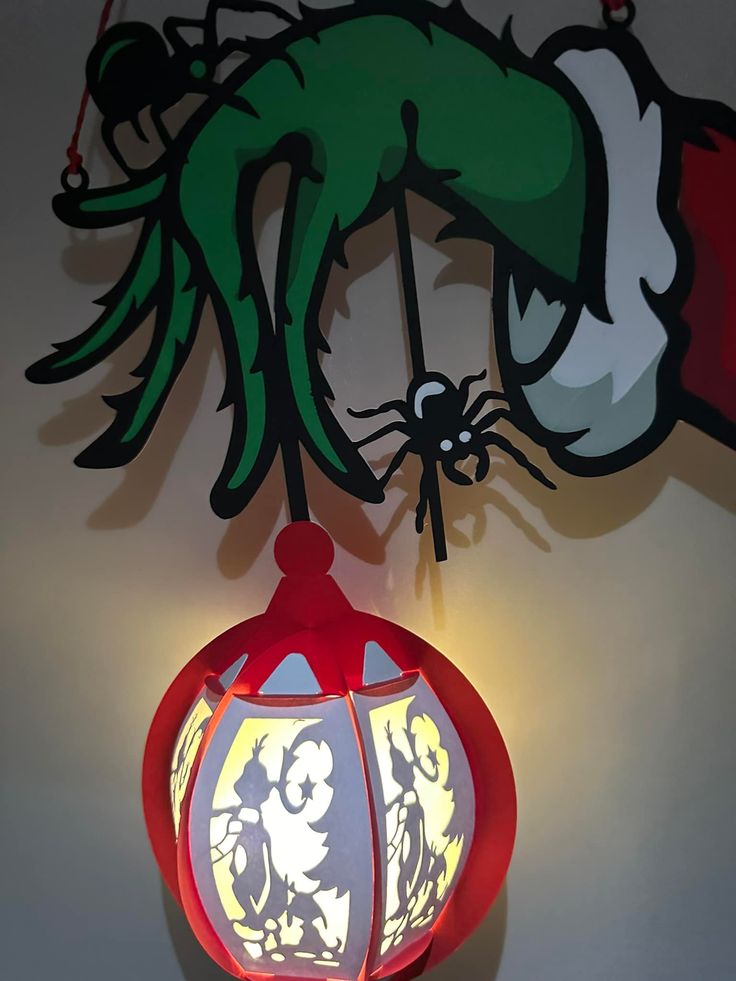 a lamp hanging from the ceiling in front of a wall with an image of a spider on it