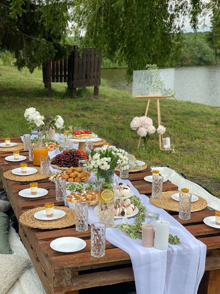 an outdoor table set up with food and drinks for a picnic or brunch