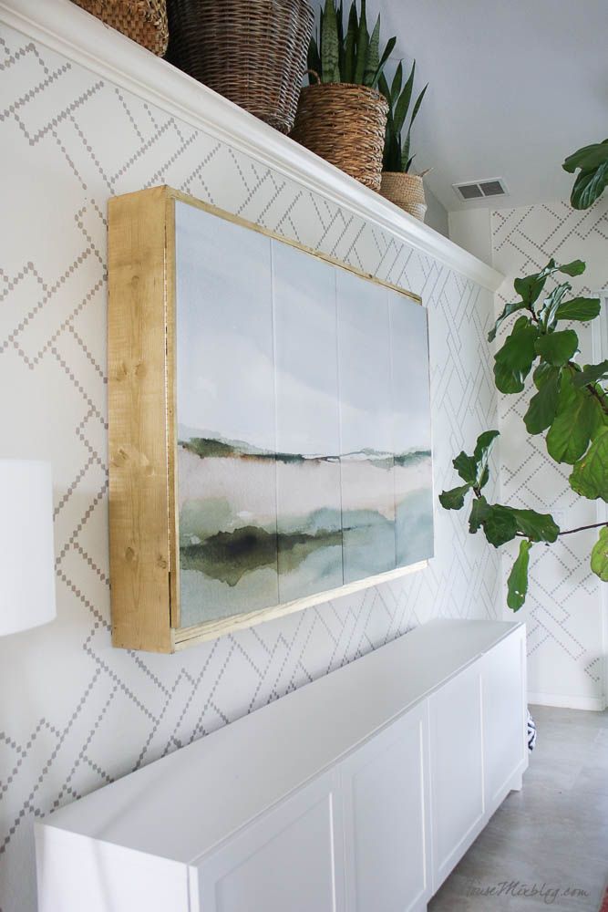 a painting hangs on the wall above a white bench with potted plants in it