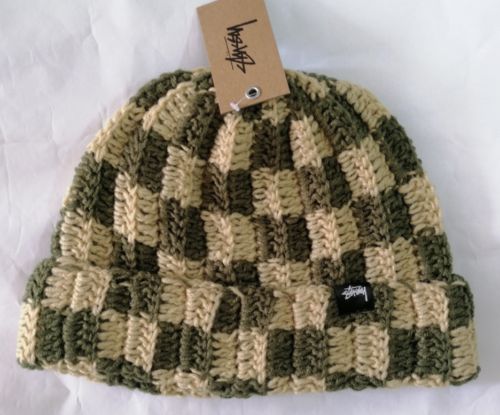 a green and white knitted hat with a tag on it