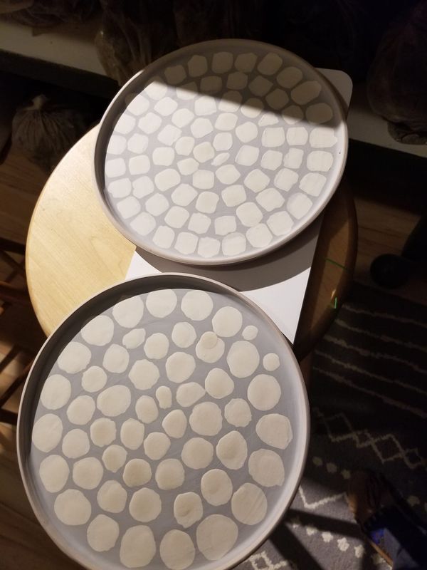 two white plates sitting on top of a wooden table next to a black and white cat