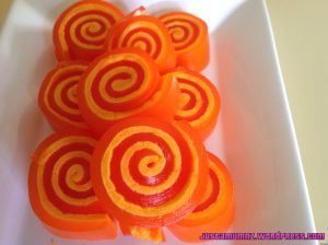 orange lollipops in a white bowl with swirl designs on the top and bottom