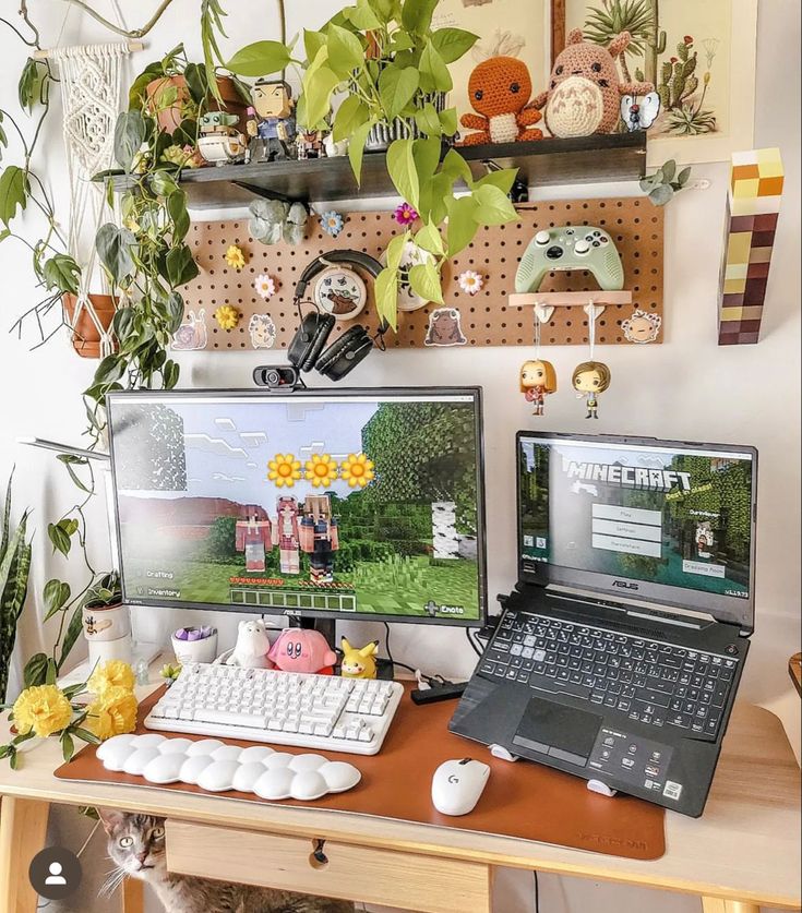 two computer monitors sitting next to each other on a wooden desk in front of a plant