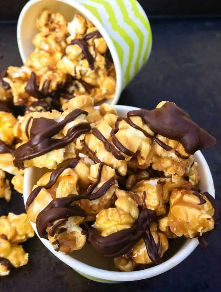 two bowls filled with caramel popcorn and chocolate drizzled on top of them