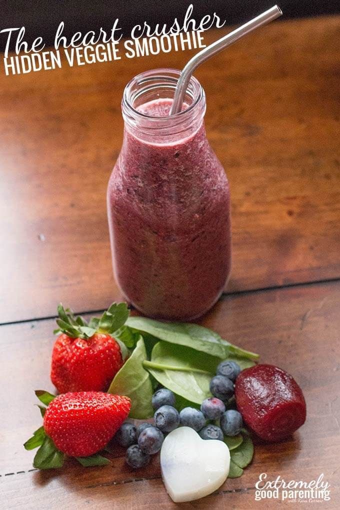 a smoothie with strawberries, blueberries and spinach leaves on the table