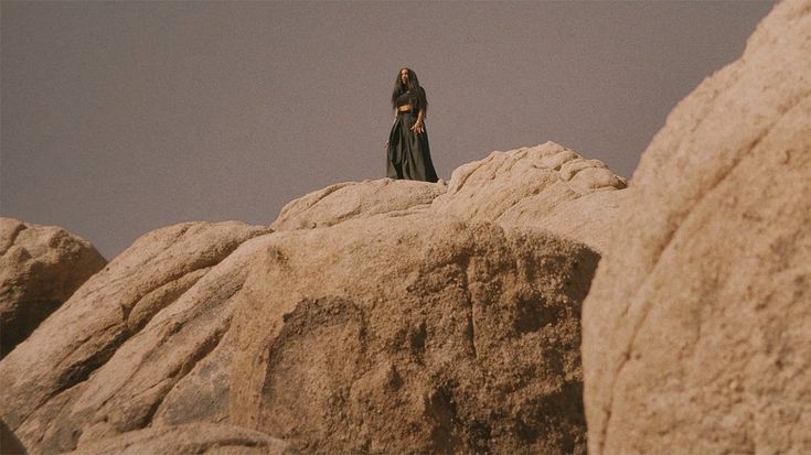 a woman standing on top of a large rock