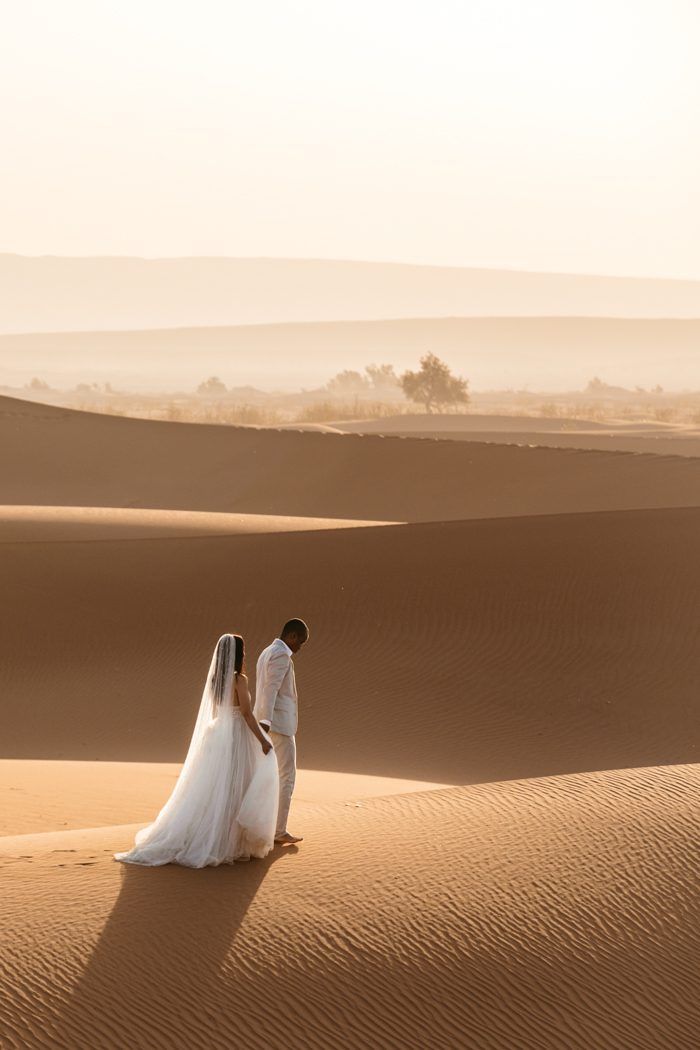 a bride and groom standing in the desert