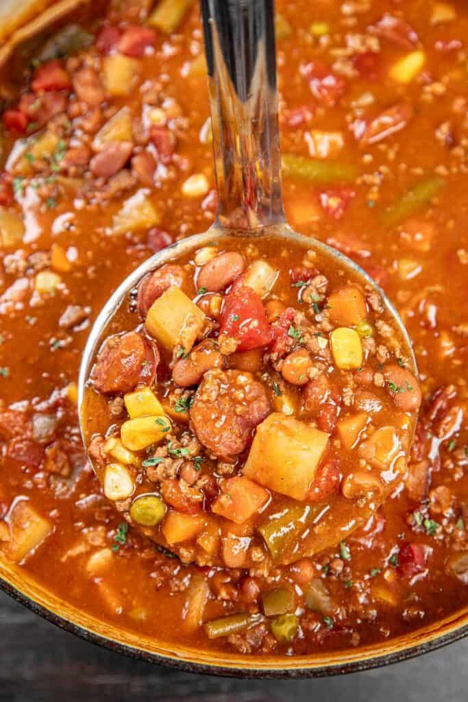 a ladle full of chili and sausage soup