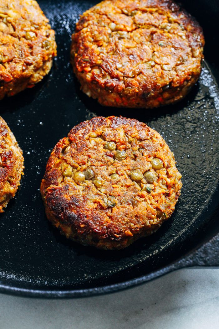 four burger patties cooking in a skillet