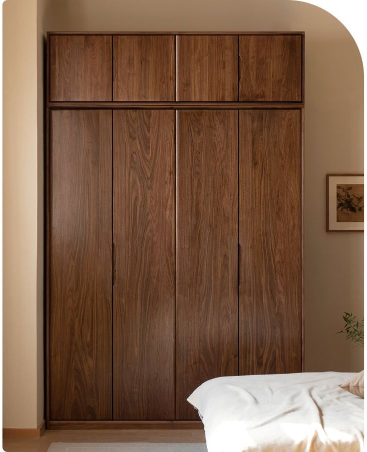 a bed sitting under a wooden closet in a bedroom