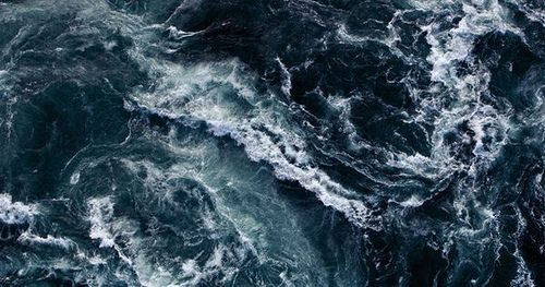 an aerial view of the ocean with waves crashing on it's surface and dark blue water