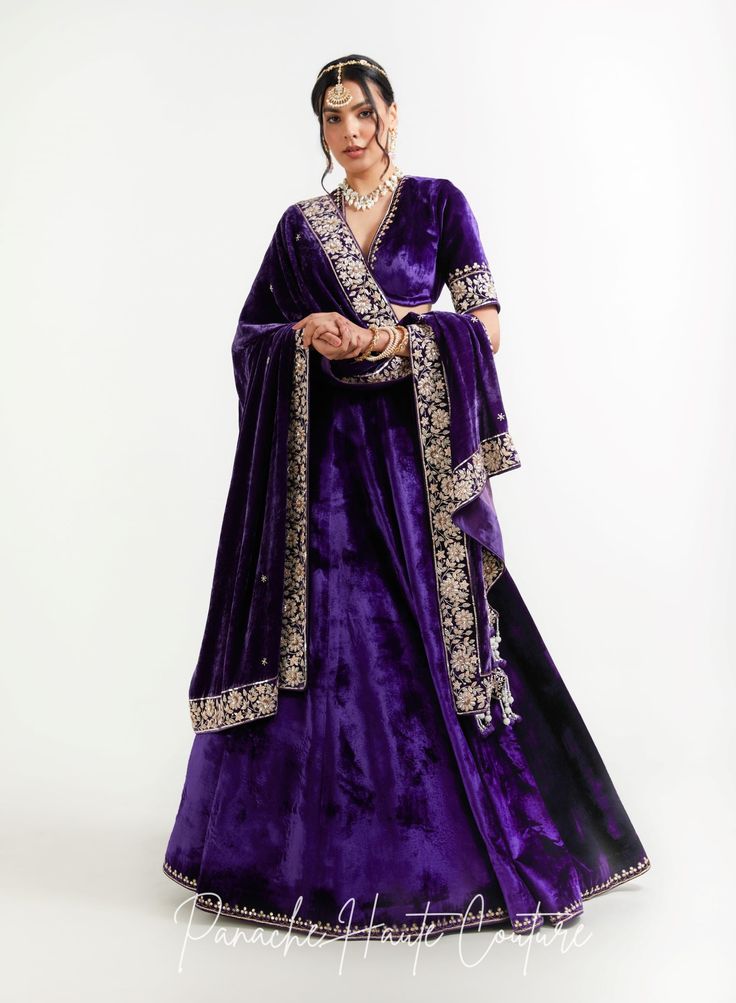 The violet color of lehenga set adds a regal touch, while the shawl can provide an additional layer of warmth and elegance. It is adorned with intricate embroidery, sequins, or other embellishments to make it stand out. When wearing a lehenga set, it's important to choose accessories that complement the outfit without overpowering it. A simple pair of earrings, a bracelet, and a clutch in a complementary color can be all that is needed to complete the look. Overall, a Violet Color Lehenga Set with a shawl from the Sensual Shadows Collection can be a stunning choice for anyone looking to make a statement with their fashion choices. The vibrant colors and intricate details are sure to turn heads and make the wearer feel like royalty. Brand: Panache Haute Couture Collection Name: The Sensual Purple Pre-draped Saree For Wedding, Velvet Anarkali Set For Reception, Traditional Purple Sharara With Sheer Dupatta, Purple Sharara With Sheer Dupatta In Traditional Drape, Purple Sharara With Sheer Dupatta And Traditional Drape, Semi-stitched Velvet Anarkali Set For Reception, Purple Sets With Sheer Dupatta For Reception, Purple Reception Sets With Sheer Dupatta, Reception Sets With Purple Sheer Dupatta