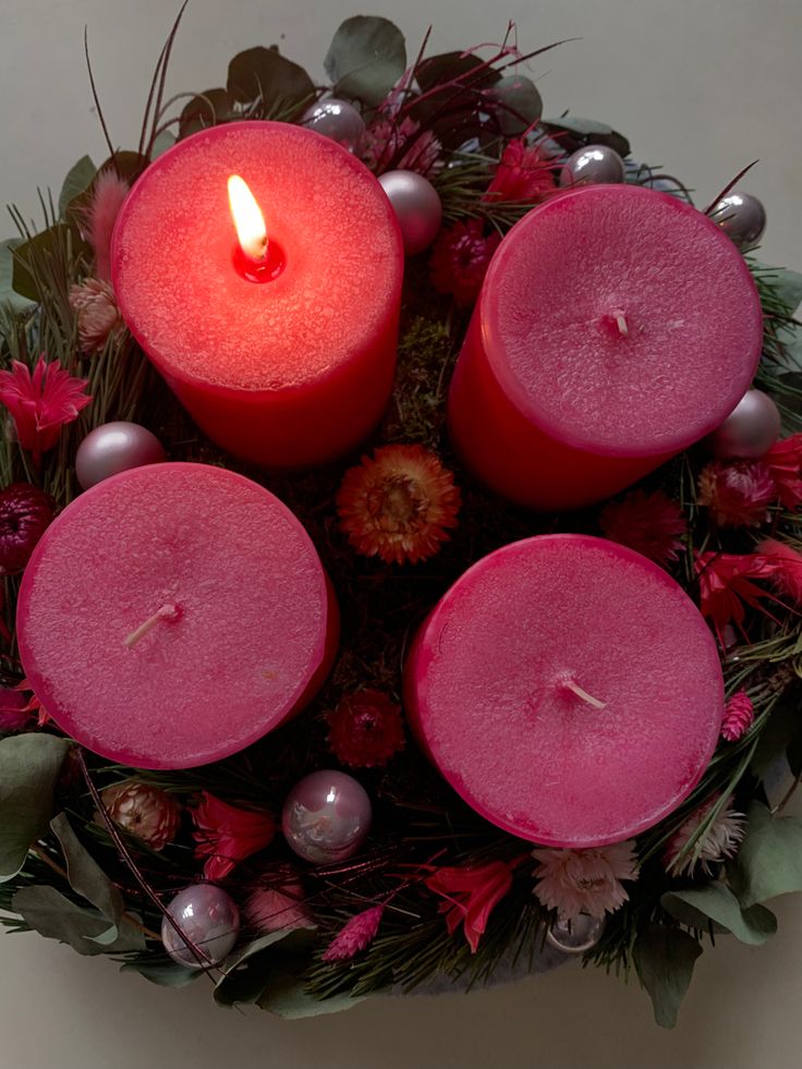 three red candles sitting on top of a bouquet of flowers