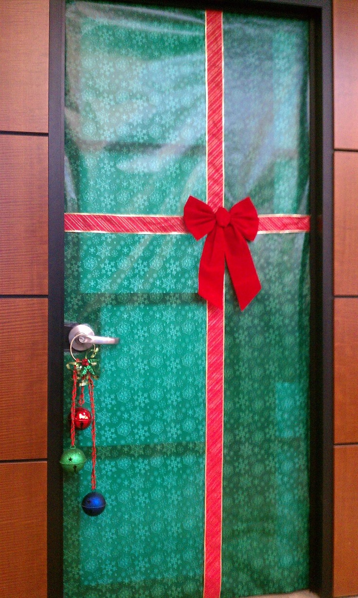 a christmas present wrapped in green paper with a red bow and bells hanging from it