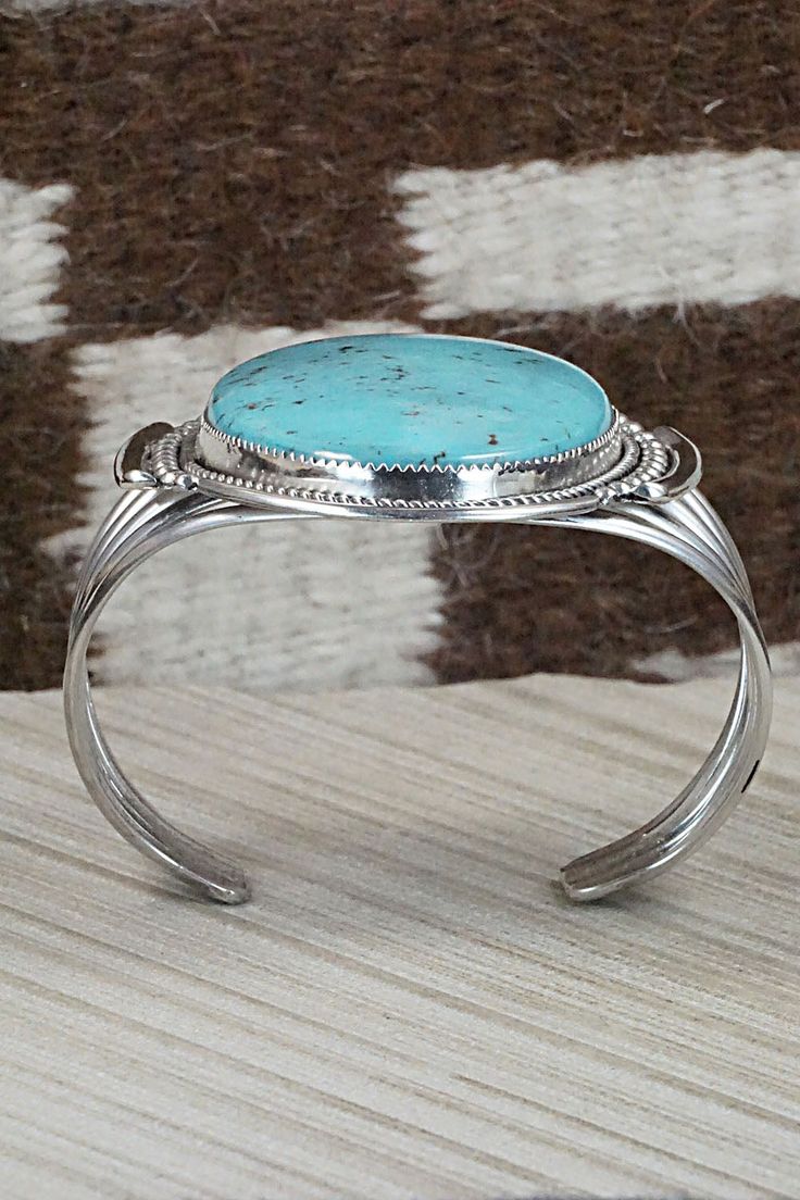 This Kingman turquoise and sterling silver bracelet was made by Zuni silversmith Kenny Calavaza. The back is signed K.C. and Zuni.Size: 5 1/2" (will fit up to a 6 3/4" wrist)Gap: 1 1/4"Length: 2 5/8"Free shipping on all orders! We ship with USPS and always include tracking. All orders ship within a day of payment.Returns are accepted up to 30 days after you receive your order. Just send us a message. Our shop offers cash back or store credit. The item must be returned in new condition. Classic Turquoise Sterling Silver Bracelets, Turquoise Sterling Silver Cuff Bracelet With Polished Finish, Elegant Sterling Silver Bracelet With Turquoise, Elegant Turquoise Oval Sterling Silver Bracelet, Sterling Silver Turquoise Bracelet Gift, Gift Turquoise Sterling Silver Bracelet, Formal Turquoise Sterling Silver Bracelets, Adjustable Oval Turquoise Sterling Silver Bracelet, Round Turquoise Sterling Silver Cuff Bracelet