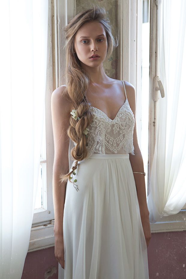 a woman standing in front of a window wearing a white dress